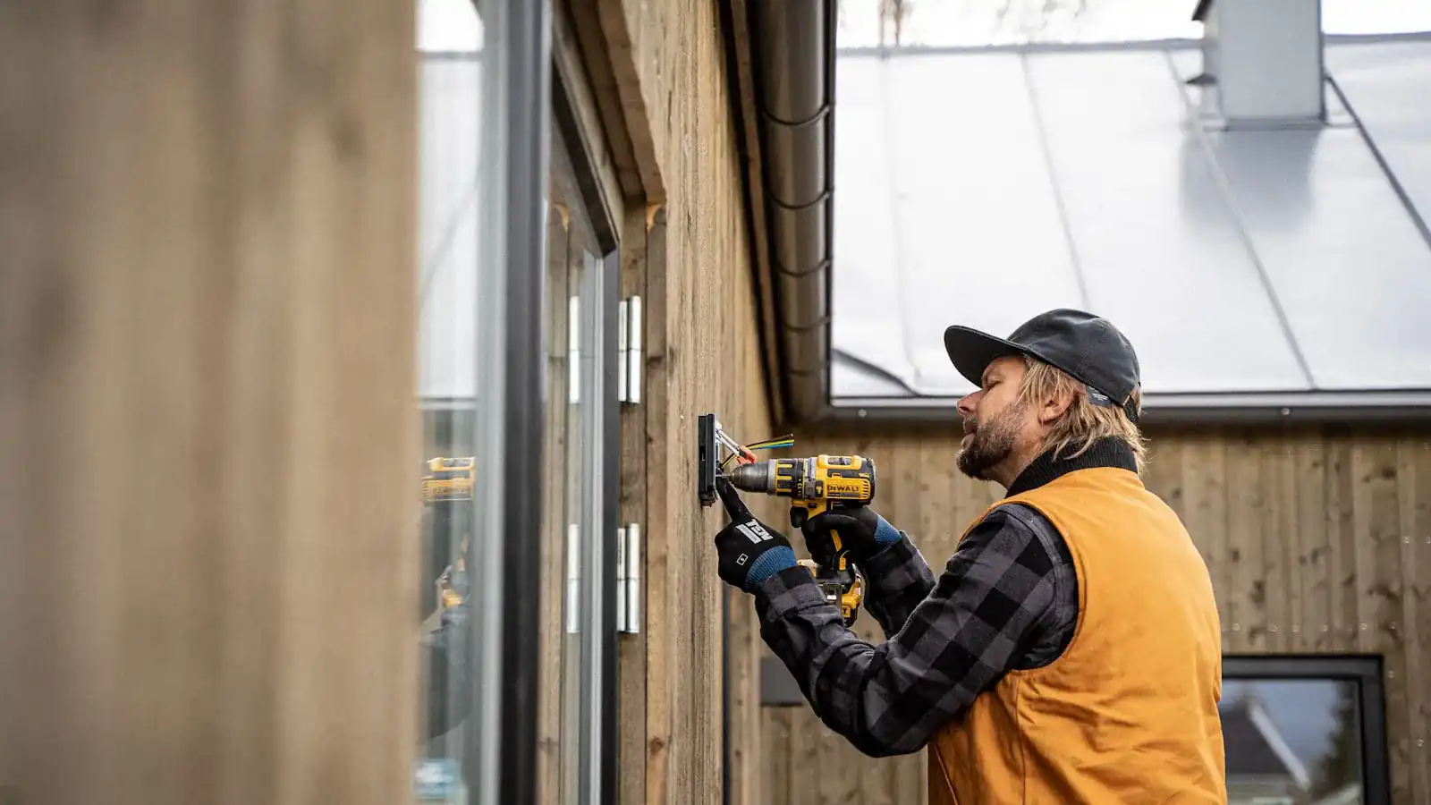 Alarm installer drilling to mount a security sensor on a window frame