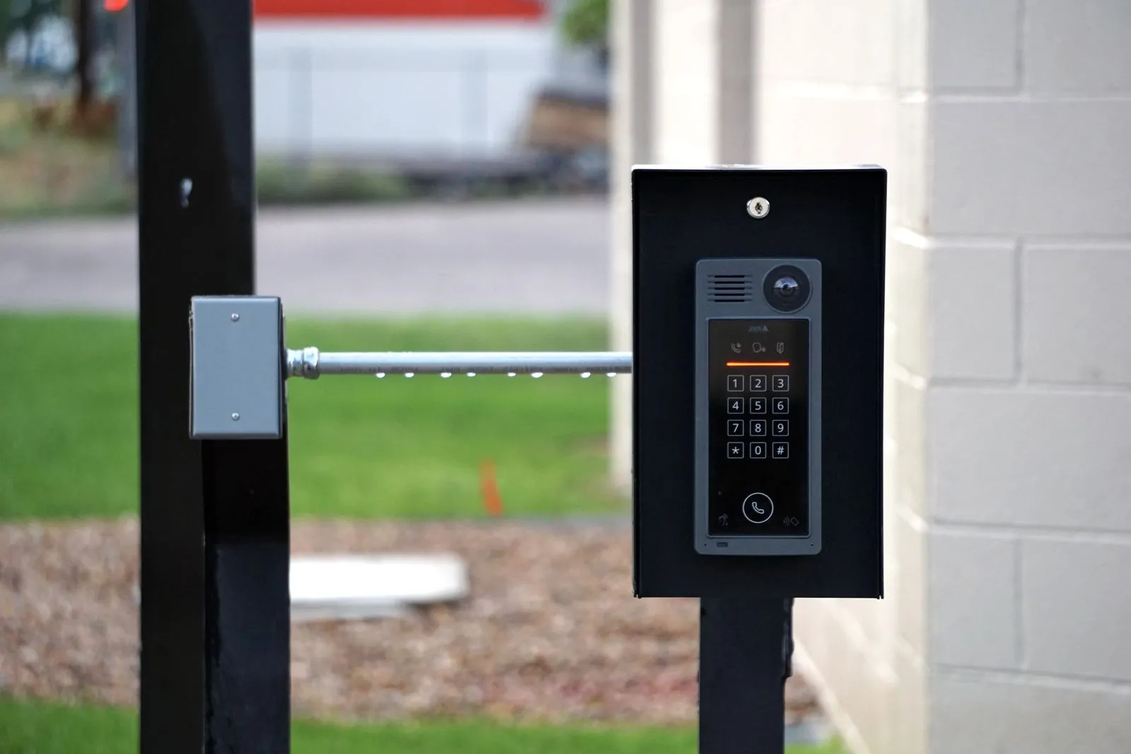 Access control keypad and intercom mounted on a post beside a driveway gate